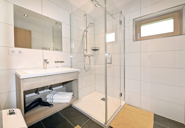 modernes Helles Bad mit weißen Wandfließen und schwarzen Bodenfließen, Glasdusche und Waschbecken mit Spiel
