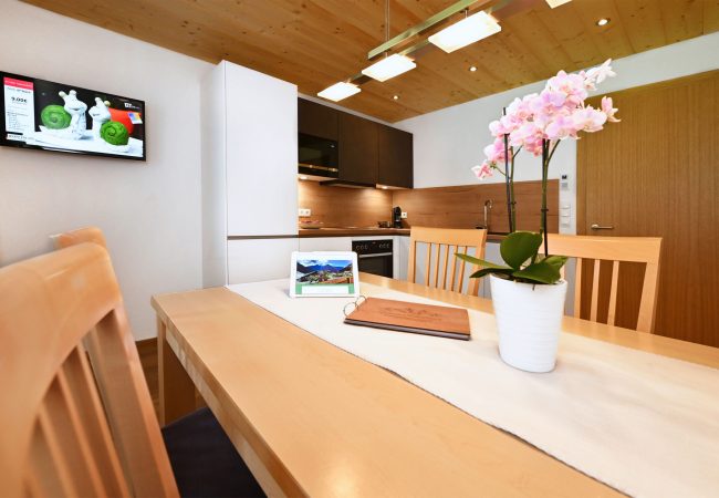 Weitwinkelblick Blick von Küchentisch mit 4 Stühlen auf moderne neue weiße Küchenzeile mit schwarzen Hängeschränken, Backofen, Herd, Mikrowelle und Spülbecken